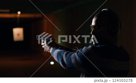 Portrait of happy shooting range customer reloading pistol, shooting targets, having fun. Close up of joyous man at shooting ground facility loading pistol, wearing protection goggles, camera B Portrait of happy shooting range customer reloading pistol, shooting targets, having fun. Close up of joyous man at shooting ground facility loading pistol, wearing protection goggles, camera B 124103278