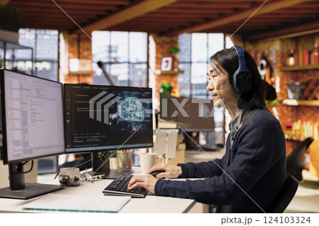 Senior programmer coding advanced AI algorithm in startup office, refining machine learning models to enhance automation, wearing headphones. Asian CTO manager listening music and coding 124103324