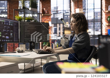 Software developer at agency office coding on her computer creating a software and works on implementing algorithms. IT expert building applications with a programming interface. 124103327