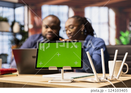 African American couple browse troubleshooting online guide next to chroma key, working together to debug router issues and restore their home network. Freelancers struggle to solve tasks. 124103405