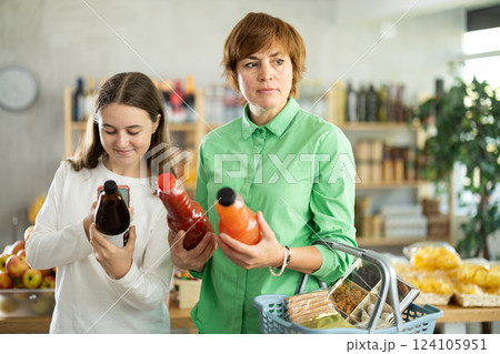 Checking expiration date of juice - mother and daughter checking qr code on bottle of juice 124105951