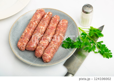 Fresh raw pork botifarra sausages ready for grilling on plate Fresh raw pork botifarra sausages ready for grilling on plate 124106002