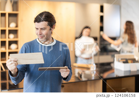 Man standing in furniture salon with examples of wood 124106158