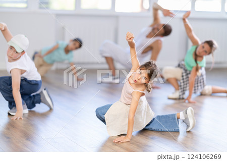 Cheerful sports preteen girls and boys hip hop dancers doing dance workout on floor with male trainer during group class Cheerful sports preteen girls and boys hip hop dancers doing dance workout on floor with male trainer during group class 124106269