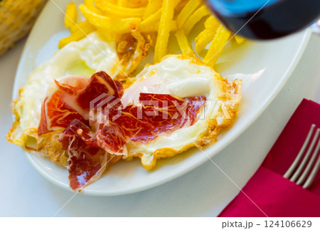 Spanish fried eggs with potatoes, ham and wine 124106629