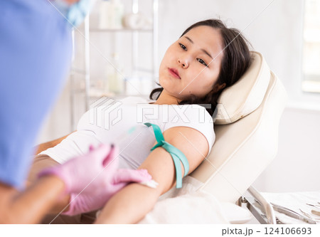Female anesthesiologist injecting anesthetic into a vein on her arm with a syringe in cosmetology clinic 124106693