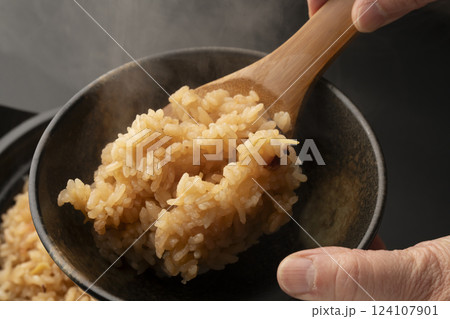 炊きたてで湯気の立った蛸の炊き込みご飯をしゃもじで茶碗に盛り付ける 124107901