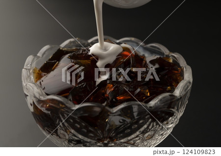 ガラスの器に盛り付けた冷たいコーヒーゼリーにミルクをかける   124109823