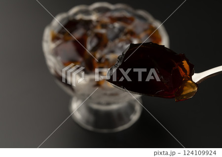 ガラスの器に盛り付けた冷たいコーヒーゼリーをスプーンで持ち上げる ガラスの器に盛り付けた冷たいコーヒーゼリーをスプーンで持ち上げる 124109924