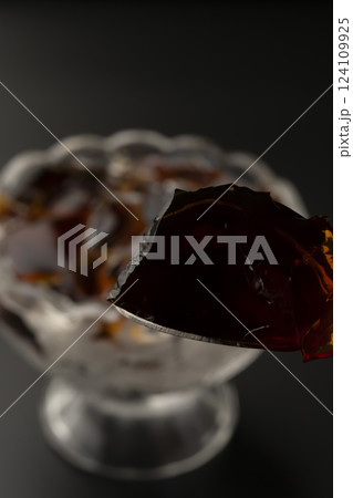 ガラスの器に盛り付けた冷たいコーヒーゼリーをスプーンで持ち上げる  124109925