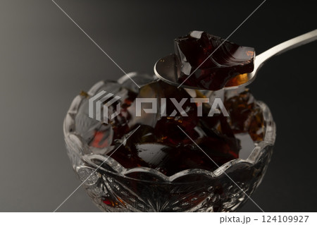 ガラスの器に盛り付けた冷たいコーヒーゼリーをスプーンで持ち上げる ガラスの器に盛り付けた冷たいコーヒーゼリーをスプーンで持ち上げる 124109927