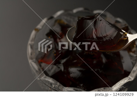 ガラスの器に盛り付けた冷たいコーヒーゼリーをスプーンで持ち上げる ガラスの器に盛り付けた冷たいコーヒーゼリーをスプーンで持ち上げる 124109929