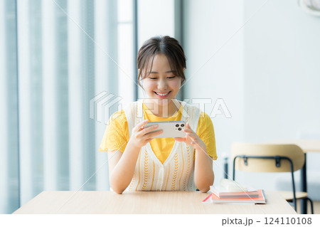 カフェでスマホを見る学生 124110108