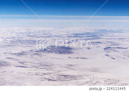 Tangla Mountain range in China, snow-capped mountain ranges like a moonscape under snow. Inner Mongolia View from an airplane window from a high altitude. Tangla Mountain range in China, snow-capped mountain ranges like a moonscape under snow. Inner Mongolia View from an airplane window from a high altitude. 124111445