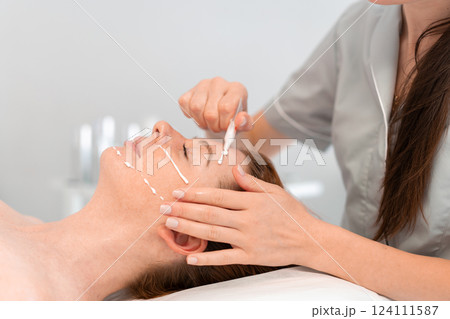 Dermatologist applying cream on woman face in 124111587