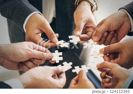The concept of teamwork and partnership. Businessman's hands putting together puzzle pieces in the office and join together in a jigsaw puzzle team. Charity. Volunteers. Business unity as a team. 124112393