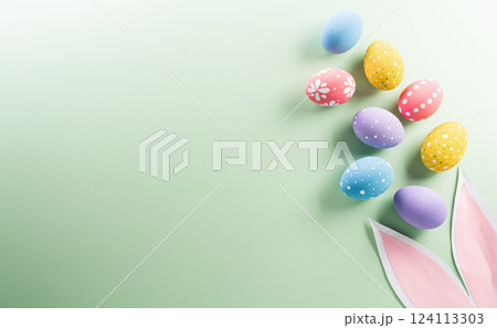 Easter party concept. Top view of easter bunny ears and colorful eggs on pastel background with copyspace for the text. Easter party concept. Top view of easter bunny ears and colorful eggs on pastel background with copyspace for the text. 124113303