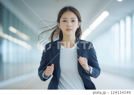 ミニマルなオフィスの廊下を前進する決意に満ちた若い女性 124114149