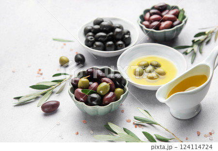 Bowls of various olives with olive oil and olive branches on marble table Bowls of various olives with olive oil and olive branches on marble table 124114724
