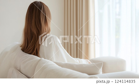 夢のような美しい雰囲気、白いローブを着た女性がクリーム色のソファにくつろぐ 124114835