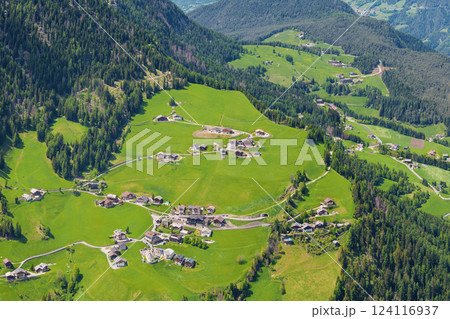 Scenic aerial view of idyllic alpine village surrounded by lush green hills near Valley of Funes at Dolomites, Italy 124116937
