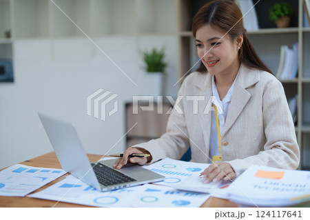 professional businesswoman planning and analyzing marketing charts and financial documents with a laptop and calculator papers on the desk professional businesswoman planning and analyzing marketing charts and financial documents with a laptop and calculator papers on the desk 124117641