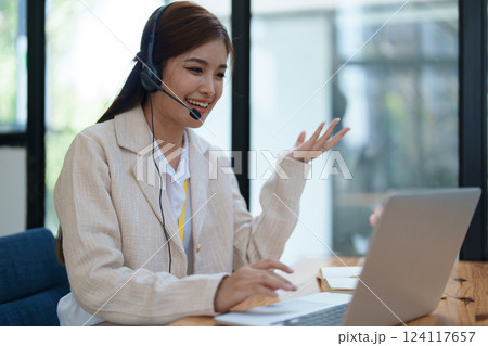 Asian businesswoman wears a headset while participation in an online video conference discussing marketing and finance strategies effectively Asian businesswoman wears a headset while participation in an online video conference discussing marketing and finance strategies effectively 124117657