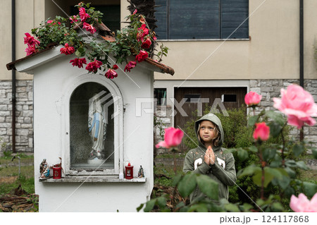 Child Praying Near Outdoor Shrine with Flower Decorations 124117868