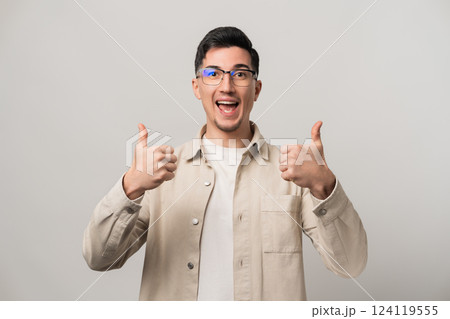 Man inspiring confidence in a product or service shows double thumbs-up with a wide smile. Wearing eyeglasses and beige clothes, he poses naturally with a candid and approachable vibe Man inspiring confidence in a product or service shows double thumbs-up with a wide smile. Wearing eyeglasses and beige clothes, he poses naturally with a candid and approachable vibe 124119555