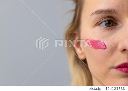 Close-Up of a Young Woman with Pink Lipstick Applying Makeup to Her Cheek for a Chic, Artistic Look and Embracing Modern Beauty Trends Close-Up of a Young Woman with Pink Lipstick Applying Makeup to Her Cheek for a Chic, Artistic Look and Embracing Modern Beauty Trends 124123788
