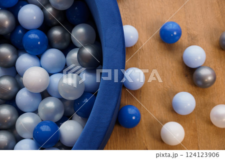 Top View of Colorful Plastic Balls in Blue Soft Play Pool on Wooden Playground Surface 124123906