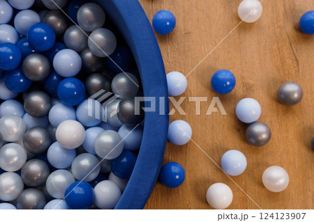 Blue, Gray and White Plastic Balls in Soft Blue Pool on Wooden Surface Blue, Gray and White Plastic Balls in Soft Blue Pool on Wooden Surface 124123907