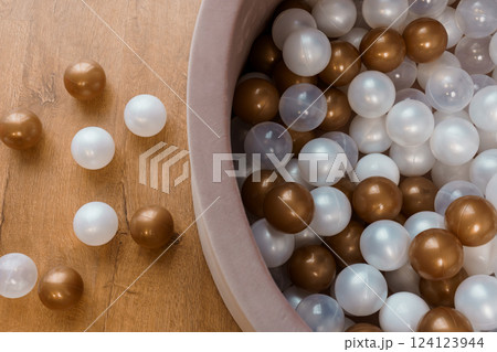 Overhead View of Brown, White, and Transparent Plastic Balls in Kids Play Pit on Wooden Floor Overhead View of Brown, White, and Transparent Plastic Balls in Kids Play Pit on Wooden Floor 124123944