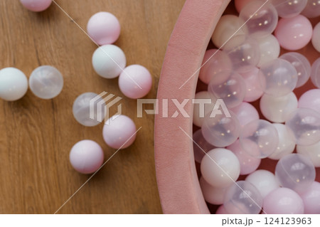 Soft Pastel Pink and White Plastic Balls in Baby's Ball Pool on Wooden Floor Background 124123963