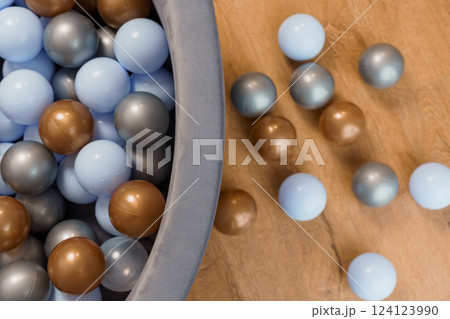 Close-up of colorful grey, blue, and brown plastic balls in a ball pit on wooden floor background 124123990
