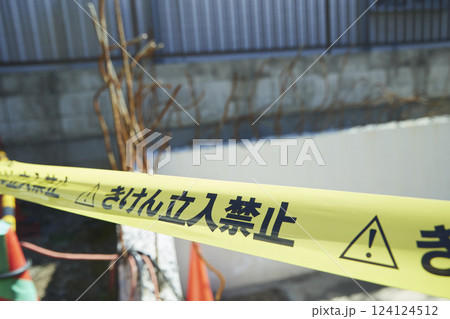 立ち入り禁止の黄色いテープ 住宅街の中途半端な空き地に貼られた立入禁止テープ	 124124512