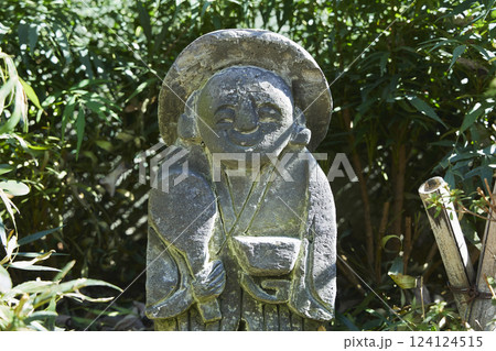 庭に飾られた地蔵の置物。石でできた優しい顔のお地蔵さん。	 124124515