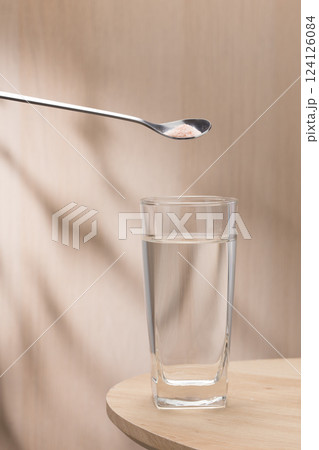 A spoon of Himalayan salt is being added to a glass of drinking water. A spoon of Himalayan salt is being added to a glass of drinking water. 124126084