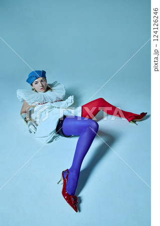 Exhausted woman, young fashionista posing lying on floor against studio background, dressed colorful tights and white corset and collar. Exhausted woman, young fashionista posing lying on floor against studio background, dressed colorful tights and white corset and collar. 124126246