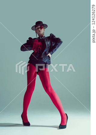 Woman in red tights and gothic jacket strikes a dominant pose, staring through heart-covered eye. Concept of fashion and style Woman in red tights and gothic jacket strikes a dominant pose, staring through heart-covered eye. Concept of fashion and style 124126279