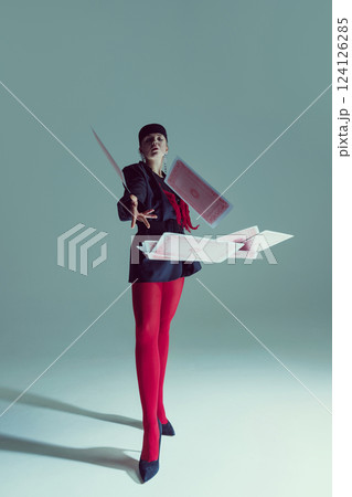 Young woman in black structured jacket, red tights, and heels dramatically throwing playing cards into air. Young woman in black structured jacket, red tights, and heels dramatically throwing playing cards into air. 124126285