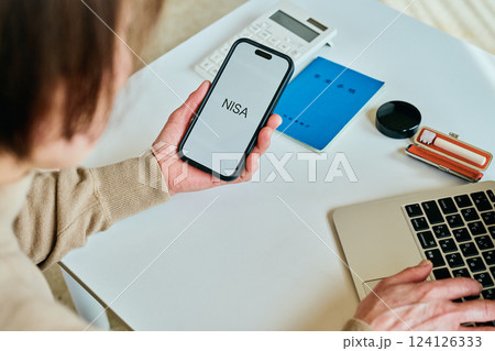 スマホを操作するシニア女性　NISA 124126333