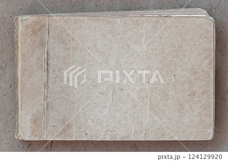 Old worn notebook, vintage texture, aged background, copy space. Aged vintage notebook with worn-out textured cover. Rustic and nostalgic background ideal for retro, antique, literary designs 124129920