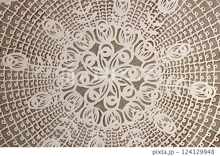 Cream craft lace doily, vintage textured background. Vintage lace doily with intricate cutout patterns on a neutral background. Delicate and classic decorative textile for elegant designs 124129948