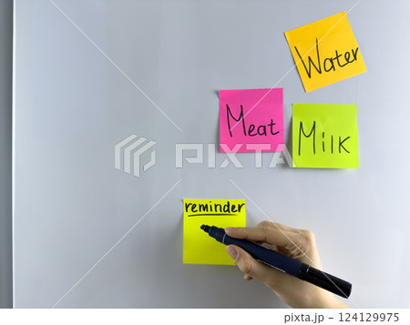 Hand writing important information on colored sticky note 124129975
