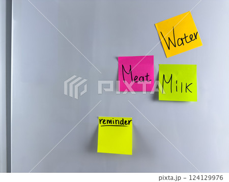 Reminder on colored sticky note hangs on refrigerator 124129976
