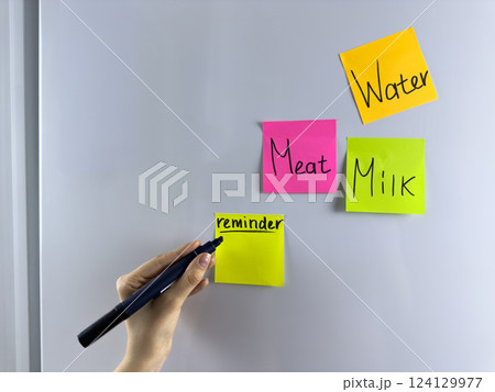 Hand writing note on colored reminder hanging on refrigerator 124129977