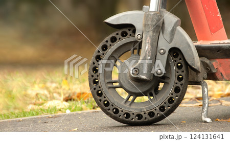 Part of an electric scooter and its front wheel on an autumn alley Part of an electric scooter and its front wheel on an autumn alley 124131641