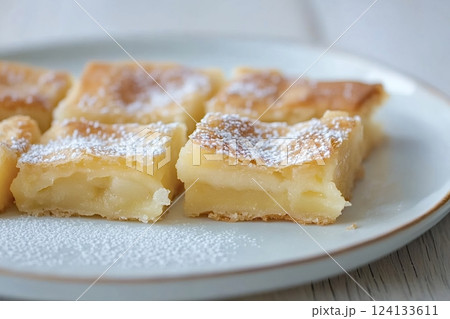 Delicious homemade custard squares sprinkled with icing sugar on plate Delicious homemade custard squares sprinkled with icing sugar on plate 124133611