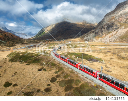 Aerial view of red train, river, mountains, orange hills in fall Aerial view of red train, river, mountains, orange hills in fall 124133733